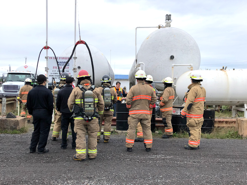 Groupe de pompiers en formation devant des réservoirs de propane